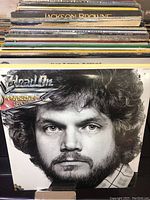 View of multiple vinyl records in a stack, showing spines with artist names including Jackson Browne and Head On by Head East album at front.