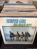 Top view of a stack of vinyl albums highlighting 'Surfer Girl' by The Beach Boys in front