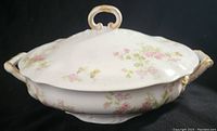 Side view of floral Limoges porcelain casserole with lid, showing floral pattern and gold handle accents.