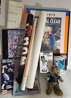 Lot of sports collectibles including magazines, posters, and boxed bobblehead seen from above