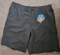 Front view of men's Columbia cargo shorts showing dark olive green color and UPF 30 tag
