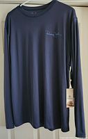 Full view of navy blue long sleeve fishing shirt with tags hanging from left side seam.
