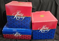 Three stacked boxes of Philip Kingsley porcelain china, red and blue packaging showing brand name.
