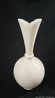 Side view showing round base and tall neck of white vase.