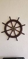 Front view of a wooden ship steering wheel mounted on wall.