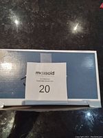 Photo shows a box from MaxSold with the lot number 20, placed on a dark surface under lighting.