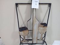 Metal wall art featuring a wine bottle and two wine glasses with steel frame hung on a wall