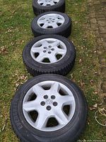 Four wheel and tire assemblies lined up on grass
