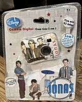 Front view of blister packaging showing white digital camera with Jonas Brothers images and branding