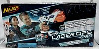 Box front showing Nerf Laser Ops Pro branding and packaging information including app connectivity and age 8+. Two users pictured holding the blasters.