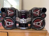 Front view of Panasonic stereo system showing main unit and two speakers with red and metallic styling.