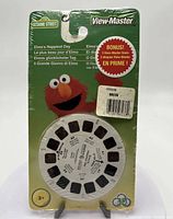 New sealed View-Master reel featuring Sesame Street's Elmo on packaging. Includes bonus 3 reels. Front view of packaging and reel showing title 'Elmo's Happiest Day'.