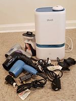 Levoit humidifier with three folding hair dryers, electric shaver and posture device visible