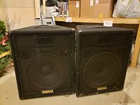 Pair of Yamaha SV15 speakers side by side, showing front metal grills and Yamaha logo.