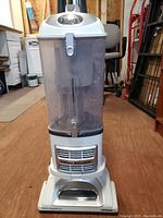 Front view of white and gray Shark professional upright vacuum cleaner with clear dust bin and visible Shark logo on top.