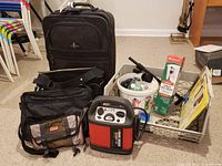 Wide view showing all items in the lot including travel bags, battery jumper, bin with tools, sandpaper, and packaged valve.