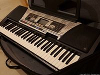 Close-up of Yamaha PSE350 keyboard showing keys, control panel, and speakers inside the open carrying case.