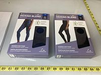 Two boxed pairs of Merino Blend women's leggings by Paradox, size Large. One pair is black and one is navy blue.