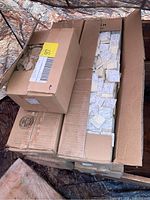 Five cardboard boxes stacked and opened containing multiple loose packs of 1.5 inch square Post-it notes.