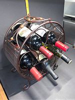 Front view of metal and bamboo wine rack holding wine bottles, showing the circular slots and the curved metal frame.