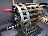 Side angled view of metal barrel wine rack holding 14 bottles with wooden slats and metal bands.