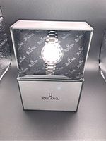 Bulova ladies wristwatch in original box on branded cushion showing watch face and bracelet.