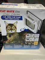 Box showing front image of the Cat Mate Elite Super Selective I.D. Disc Cat Flap with Timer Control. The packaging shows a tabby cat wearing the I.D. disc collar.