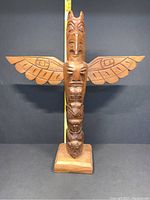 Front view of totem with ruler showing full height and carved eagle, bear, and human figures