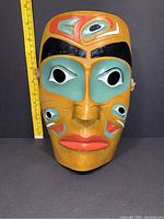 Front view of West Coast Native ceramic mask showing painted facial features and size reference.