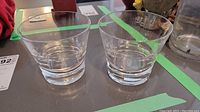 Pair of Baccarat whisky glasses shown side-by-side on table, clear glass with thick bases.