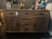 Front view of wooden sideboard showing three top drawers, three center drawers, two side cabinet doors and metal legs