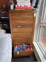Front view of walnut six-drawer dresser with one drawer open showing dovetail joinery and contents