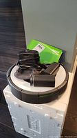 Top view showing Roomba main unit with charging dock, two battery packs and manual placed on top.