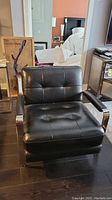 Front view of black leather armchair with square tufting and chrome frame
