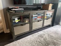 Front view of media console with books in compartments and electronics on top