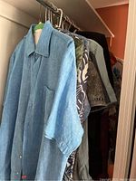 Side view of rack showing light blue short sleeve shirt, floral and printed shirts in various colors
