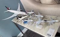 Overview of six model airplanes arranged on a marble table surface with airline liveries including Air Canada and British Airways.