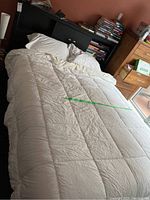 Full view of queen bed with white synthetic duvet and pillows on it.