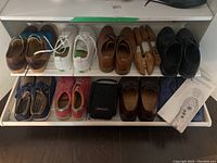 Photo showing eight pairs of men's shoes including casual and dress styles, Nike shoe cleaning kit pouch, wooden shoe lasts, and reflexology insole box.