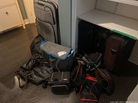 Overview of collection of suitcases and assorted soft-sided bags on floor and shelf.
