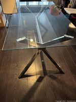 Top-down view of the rectangular glass tabletop and polished steel base visible underneath.