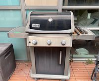 Front view of grill with closed lid, showing overall structure and casters