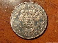 Obverse side of 1971 Canadian $1 British Columbia Centennial coin showing detailed coat of arms and inscriptions.
