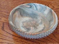 Top angled view of the Comanche pottery bowl showing interior surface, scalloped zigzag rim, and marbled coloration.