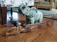 Group view of all three elephants on wood floor with fabric furniture background.