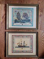 Two vintage framed naval battle and ship prints on wooden floor, showing the full front of each print and frame.