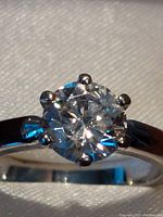 Close-up showing round faceted moissanite gemstone in sterling silver six-prong setting.