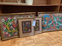 Four framed pieces of fabric art with colorful bird and floral prints, varying frame styles and sizes