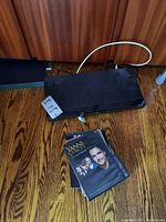 Sony BDP-S360 Blu-ray Disc player with power cord on hardwood floor next to wooden cabinet. Three DVDs in front including Yanni Voices Live in Concert.