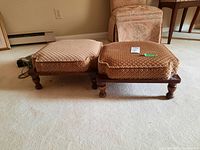 Two square brown cushioned foot stools with wood frames and legs on beige carpet.
